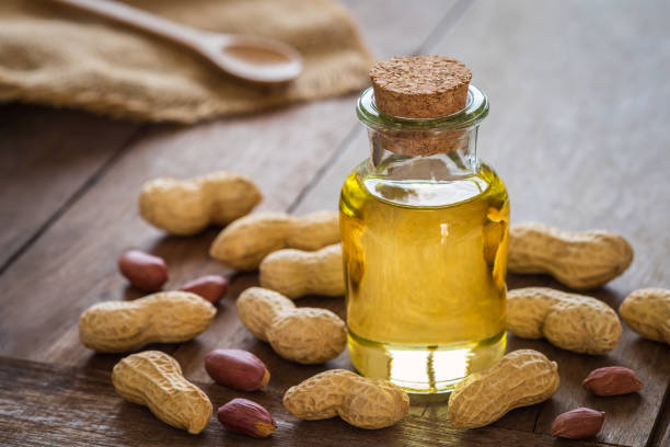 Peanut oil in glass bottle and peanuts on wooden table